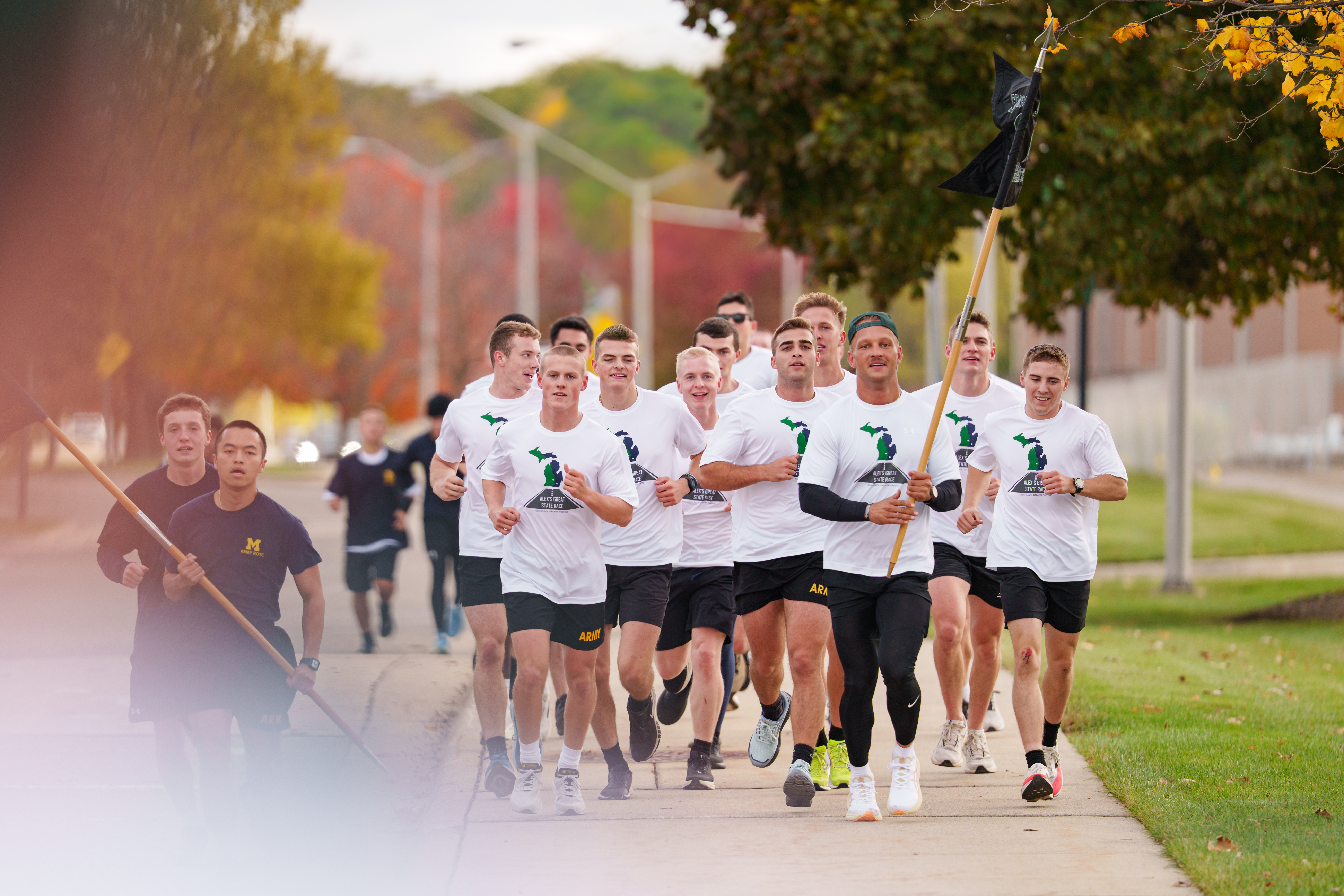 One MSU cadet holding flags and game ball running toward finish line