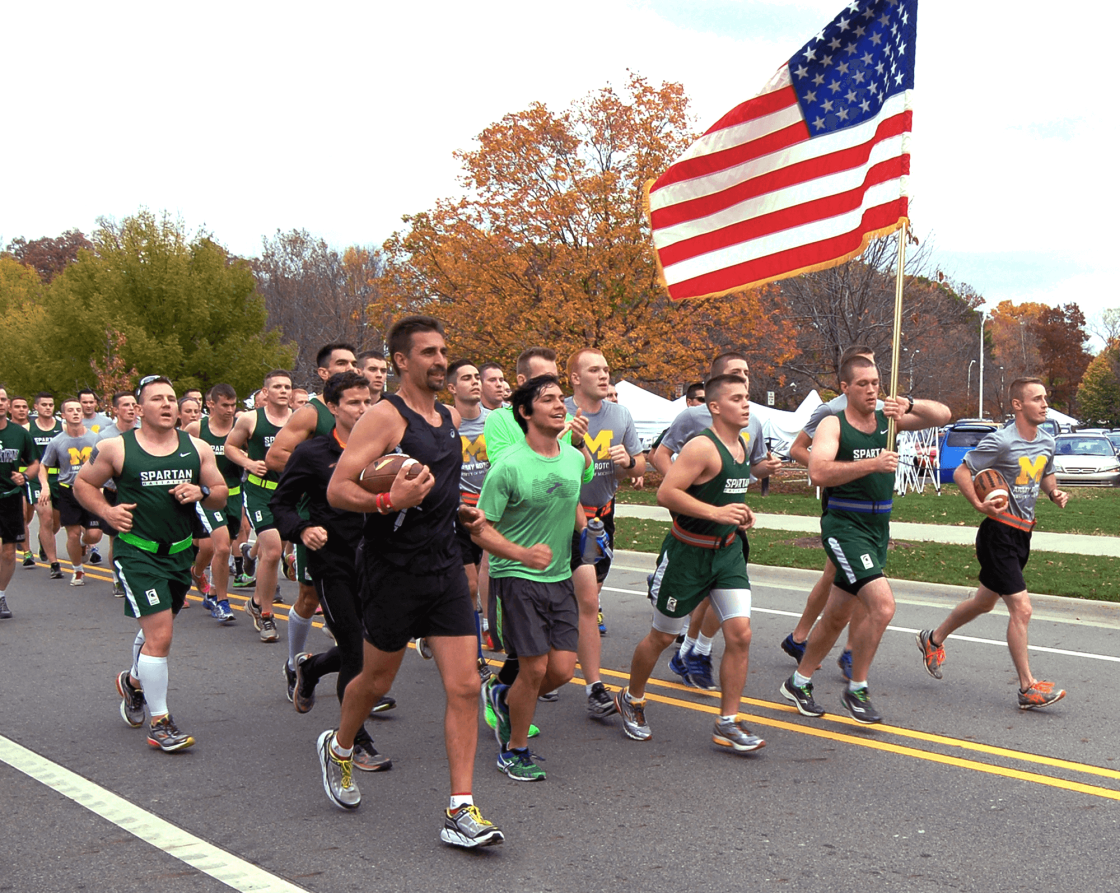 A group of MSU students running together, carrying an American flag