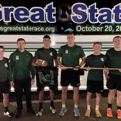 A group of MSU cadets standing in front of AGSR bus holding game ball before the start of the race