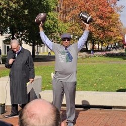 Martino Harmon, VP of Student Affairs at UM holding his arms in the air with both official game balls