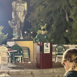 ROTC Cadet speaking at podium in front of Sparty Statue on MSU Campus at Launch Ceremony