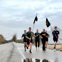 UM and MSU runners carrying flags on a wet backroad in MI