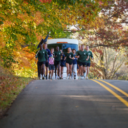 ROTC Cadets from MSU and UM running along the road with a Dean Trailways bus behind them